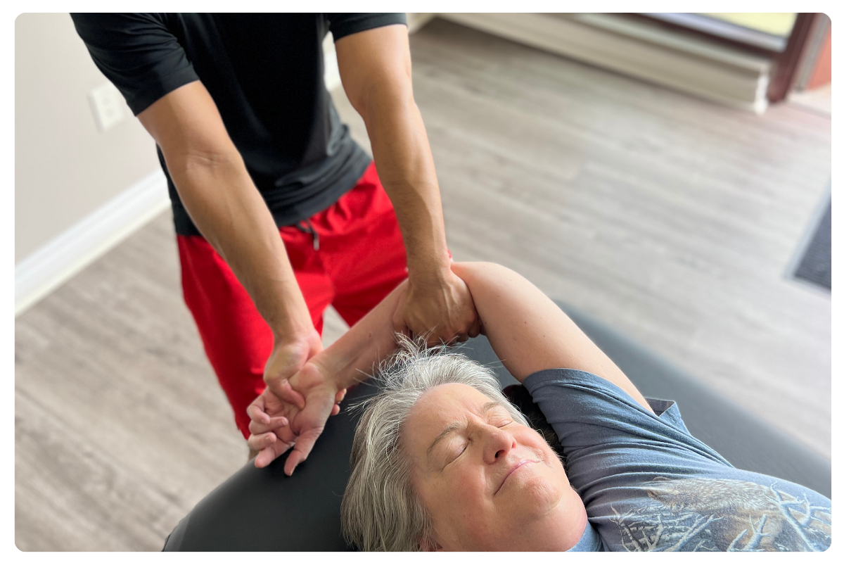 A senior female client relaxing as a Stretch U practitioner performs a professional, assisted shoulder stretch in the Greeley studio.